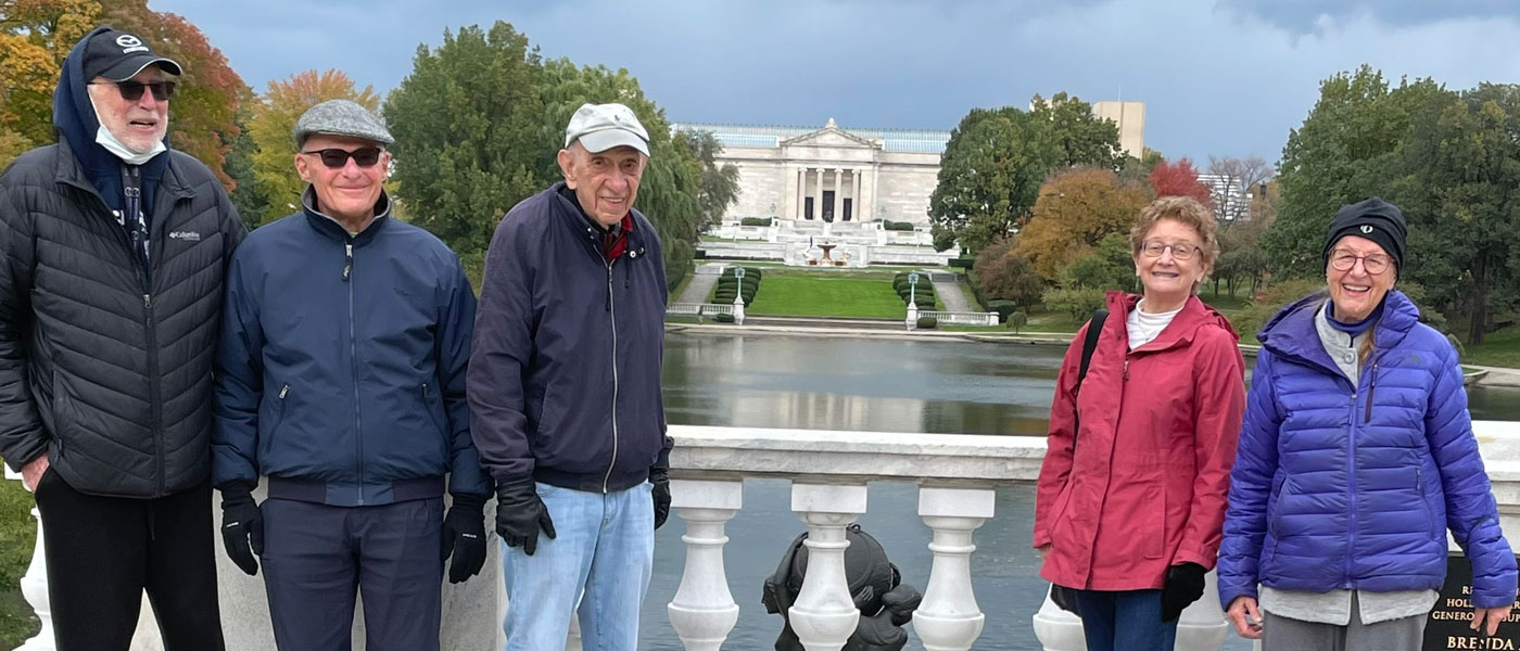 Photo of James Simmelink, Matthew Sobel, Irv Kushner, Nancy Oleinick, Marion Good pose for a photo in front of Wade Lagoon with the Cleveland Museum of Art in the background
