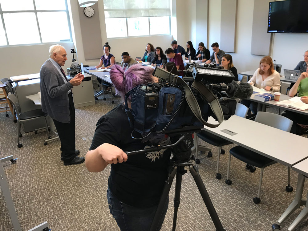 Photo of Leon Gabinet teaching a class while a camera crew records
