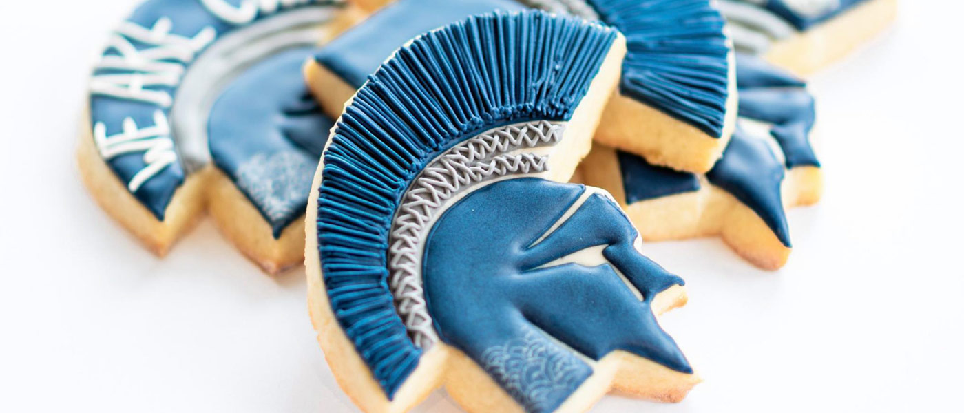 Photo of intricately decorated cookies in the shape of the Spartan head logo with icing in CWRU blue