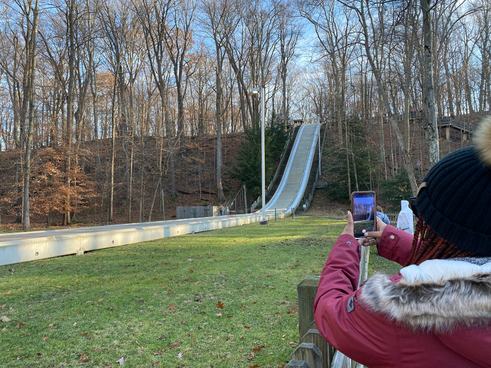 Photo taken over the shoulder of someone taking a photo on their phone of the toboggan chute in Strongsville