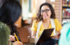 Photo of two students in conversation while one holds a clipboard