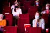 Photo of masked and physically distanced individuals sitting in a movie theater
