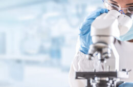Woman in lab coat looking in microscope