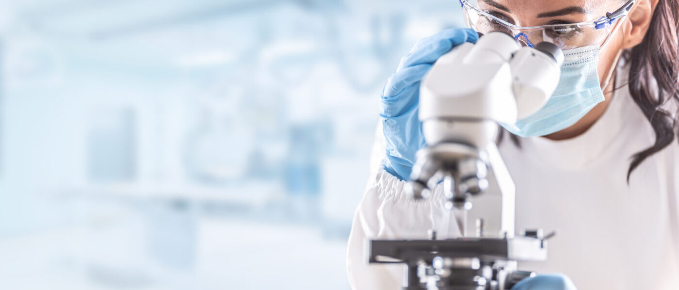 Woman in lab coat looking in microscope