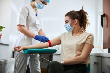 Photo of a masked individual giving blood