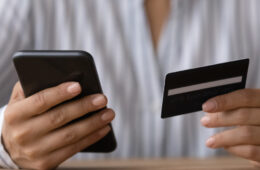 Close up photo of someone holding a phone in one hand and a credit card in the other