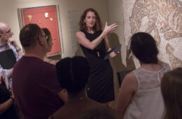 Photo of a faculty member leading a class as students gather around a piece at the Cleveland Museum of Art