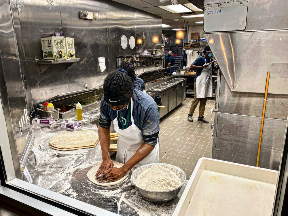 Photo of a Dewey's employee preparing the crust of a pizza