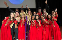 Photo of the Dhamakapella team posing for a photo with a trophy