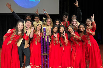 Photo of the Dhamakapella team posing for a photo with a trophy