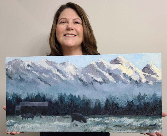 Photo of Laura Fuchs holding her painting of a landscape of Jackson Hole