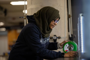 Photo of a CWRU student loading filament for a 3D printer at Sears think[box]