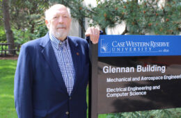Photo of Tom Kicher next to the Glennan Building sign