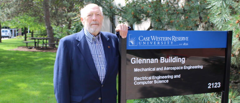 Photo of Tom Kicher next to the Glennan Building sign