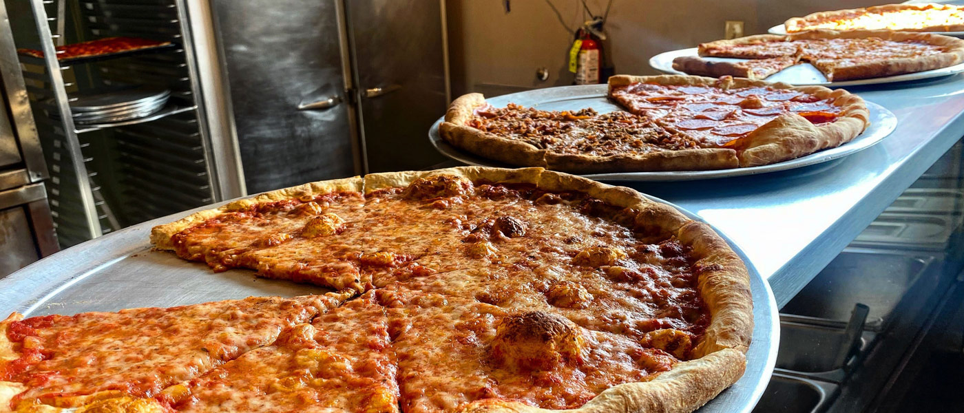 Photo of pizzas lined up on pans at Vincenza’s