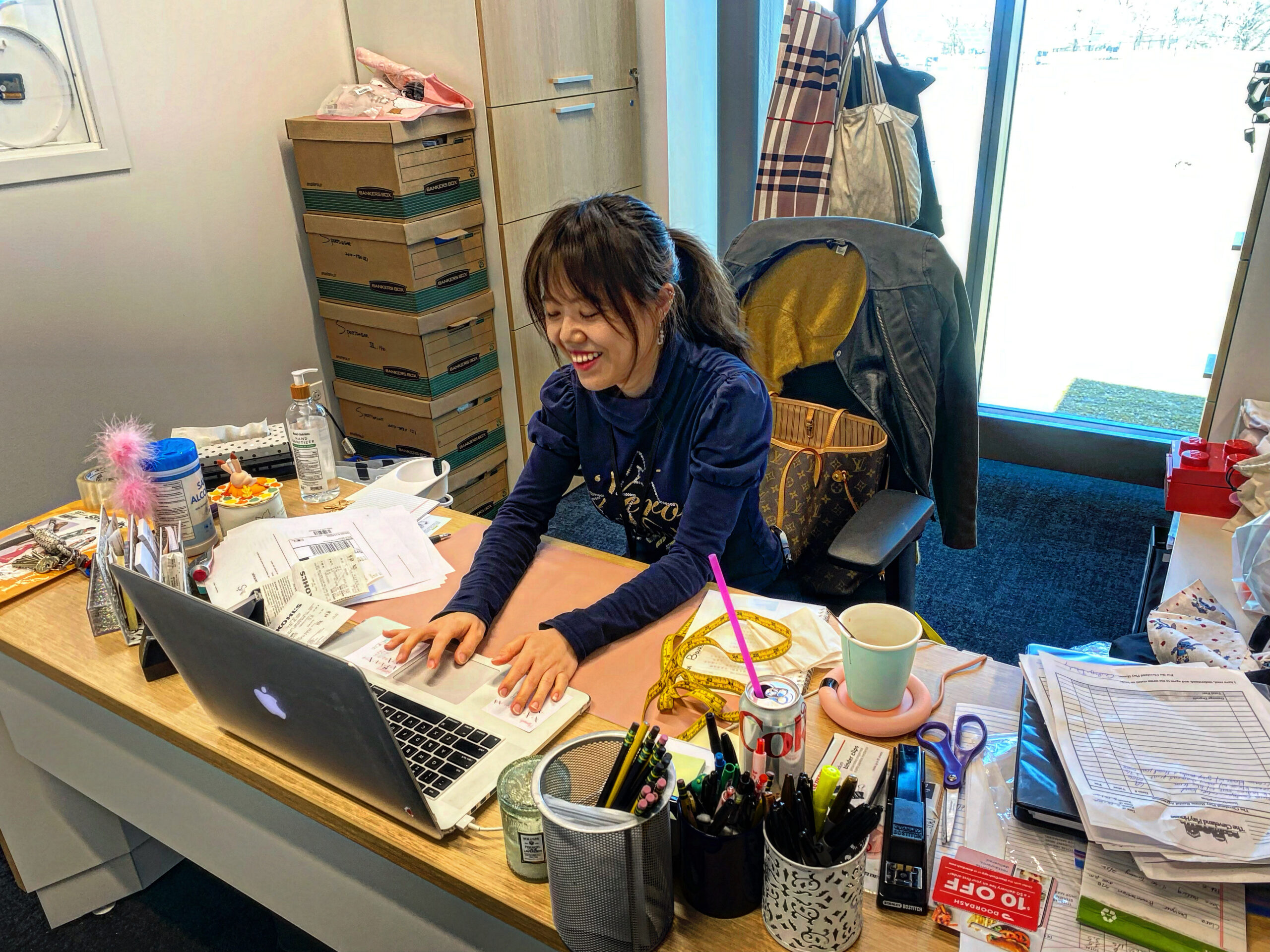 Photo of Case Western Reserve University costume shop manager Rainie Jiang sitting at her office desk