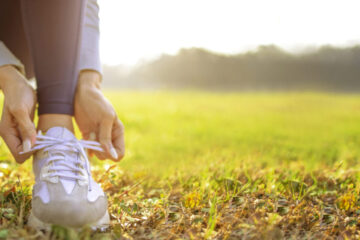 Closeup photo of someone tying their shoes with a sun glare on the image