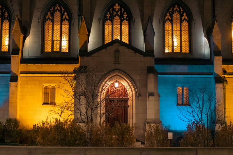 Photo of Amasa Stone Chapel at Case Western Reserve University lit in blue and yellow.