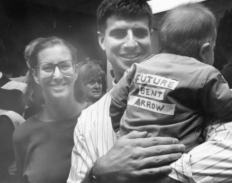 Black and white photo of a Case Western Reserve University School of Medicine student holding an infant wearing a shirt that says Future Bent Arrow