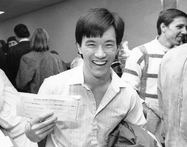 Black and white photo of a Case Western Reserve University School of Medicine student holding up a piece of paper on Match Day