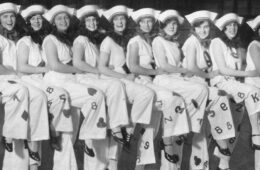 13 Mather College for Women students (now Case Western Reserve University) stand in a row wearing costumes at Stunt Night