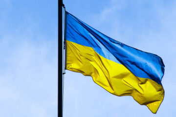 Photo of a Ukraine flag flying with blue sky in background