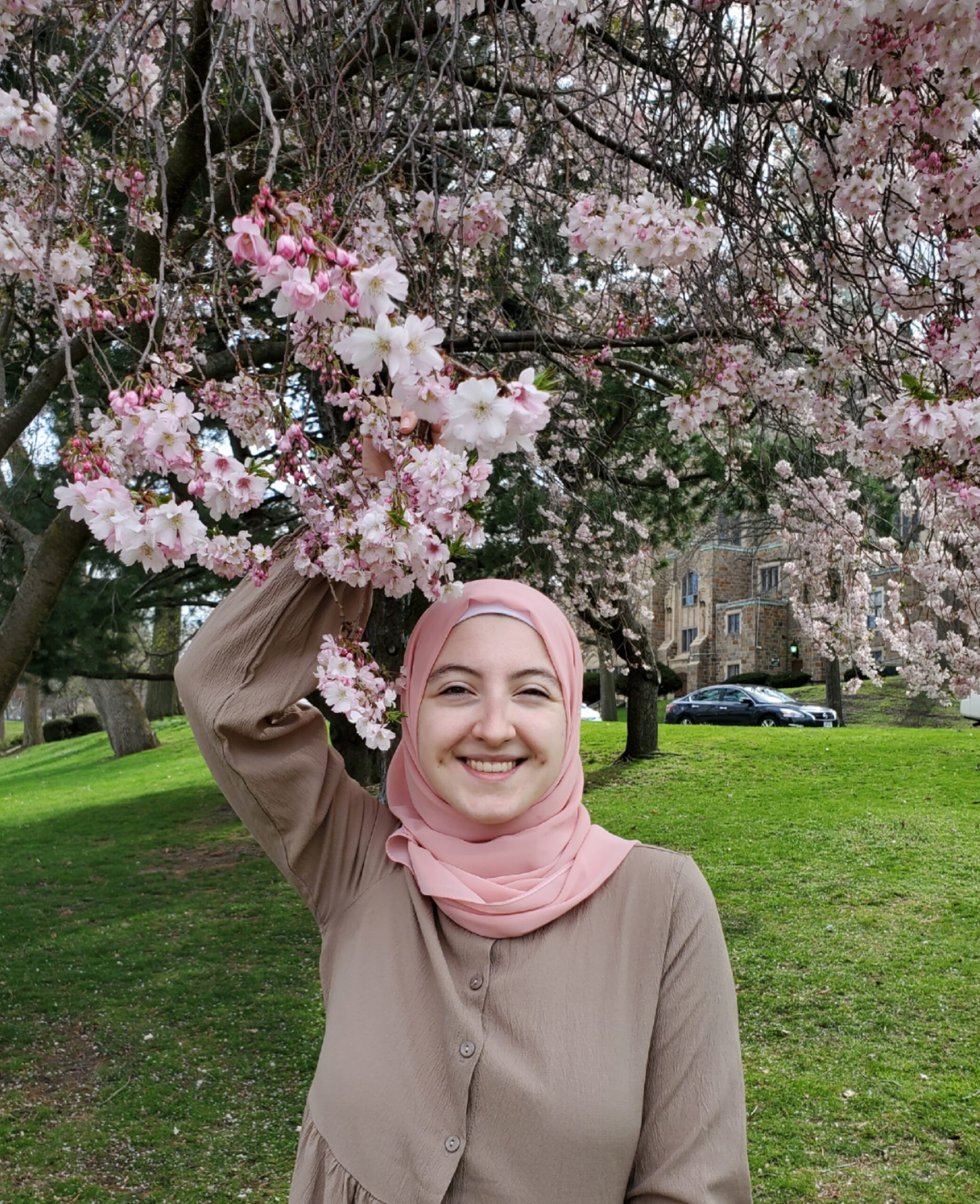 Nour Lababede standing in front of a cherry blossom tree