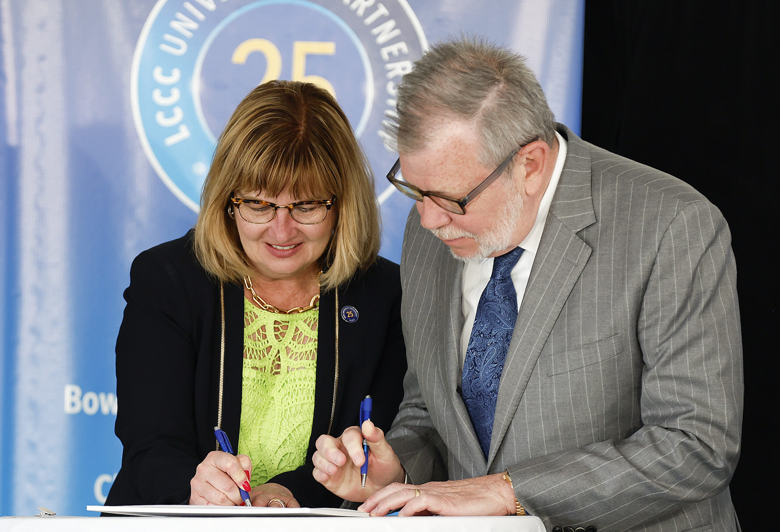 Photo of CWRU President Eric W. Kaler and Lorain County Community College President Marcia Ballinger sining a cooperative agreement.