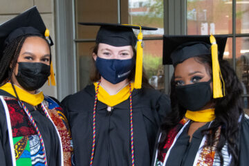 Photo of three Case Western Reserve University graduates wearing masks posed at commencement 2021