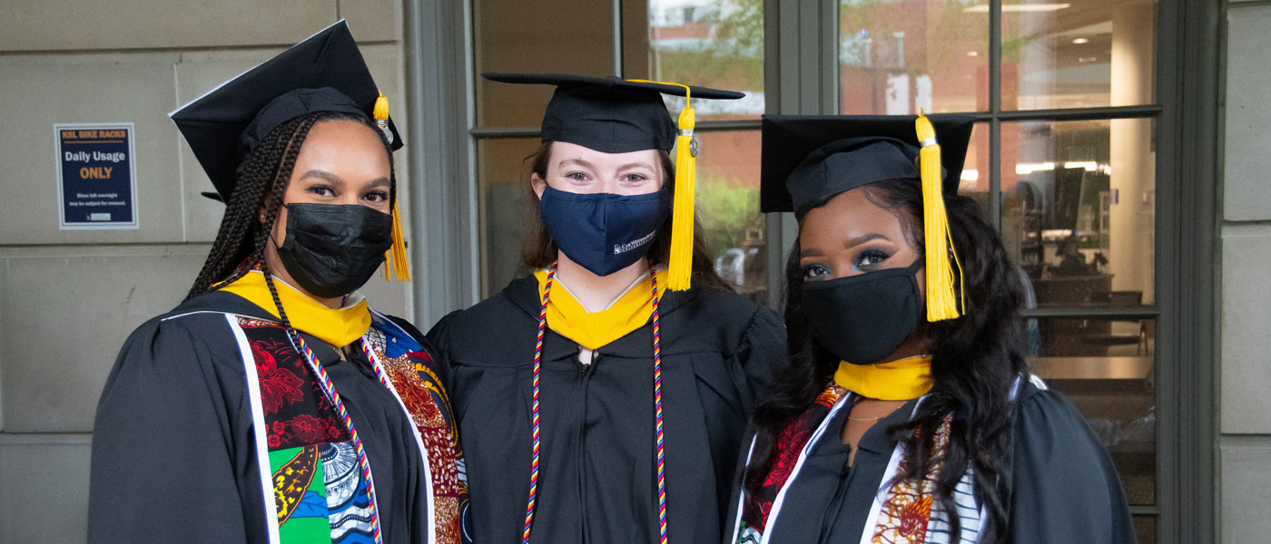 Photo of three Case Western Reserve University graduates wearing masks posed at commencement 2021