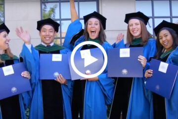 Five Case Western Reserve University students in doctoral robes holding diplomas and cheering