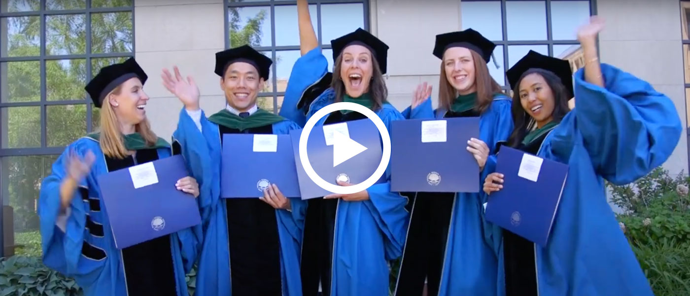 Five Case Western Reserve University students in doctoral robes holding diplomas and cheering