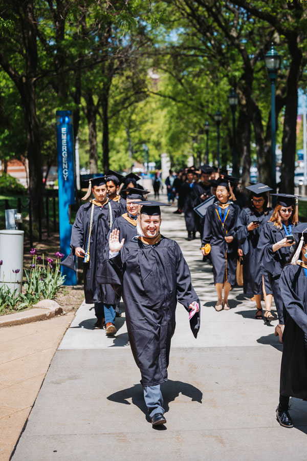 Students wearing caps and gowns walking outside toward Case Western Reserve University commencement ceremonies 2022