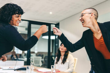 Photo of two women giving each other a fist bump during a meeting