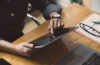 Cropped shot of young female hands using a digital tablet on wooden table. Technology concept