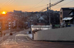 Photo looking down a nearly empty road in Seoul, South Korea, with buildings in the background and the sun setting