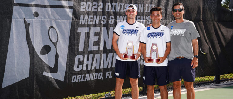 Photo of James Hopper and Jonathan Powell holding trophies next to their coach after their national championship win