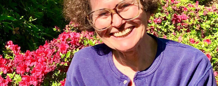 Photo of Rebecca Barchas sitting outdoors in a flower garden