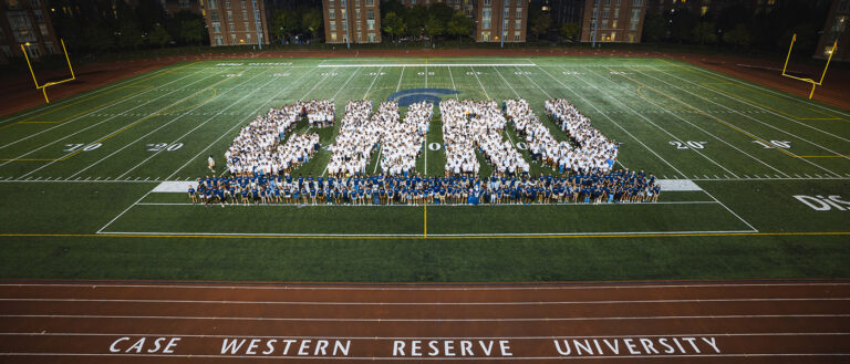 Photo of the Class of 2026 and OLs spelling out the letters C-W-R-U on DiSanto Field