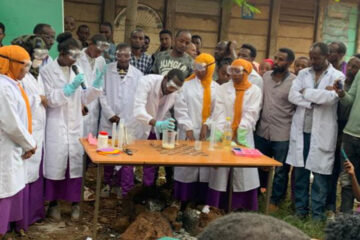 Photo of Zemene Tegegn and students at an Ethipoian high school conducting an experiment