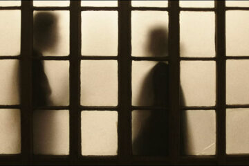 Two shadowy figures shown through windowpanes