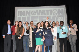 Group of people posing under an Innovation Week poster