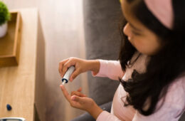 Photo of a child checking her blood sugar level by pricking her finger