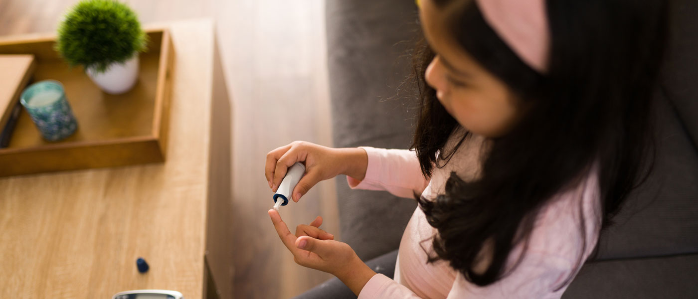 Photo of a child checking her blood sugar level by pricking her finger