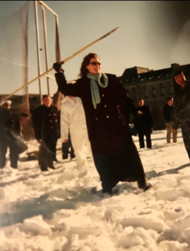 Old photo of Shannon French holding a spear while teaching a class abroad