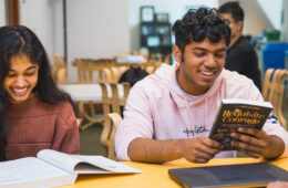 Photo of two students smiling while reading