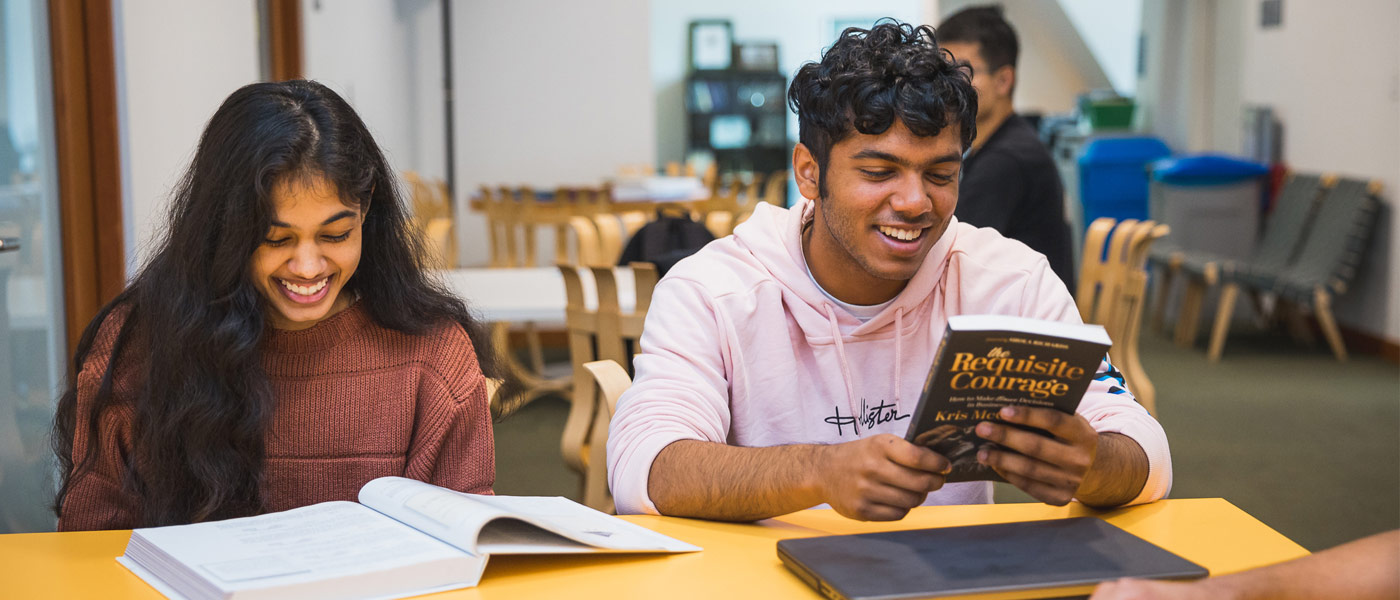 Photo of two students smiling while reading