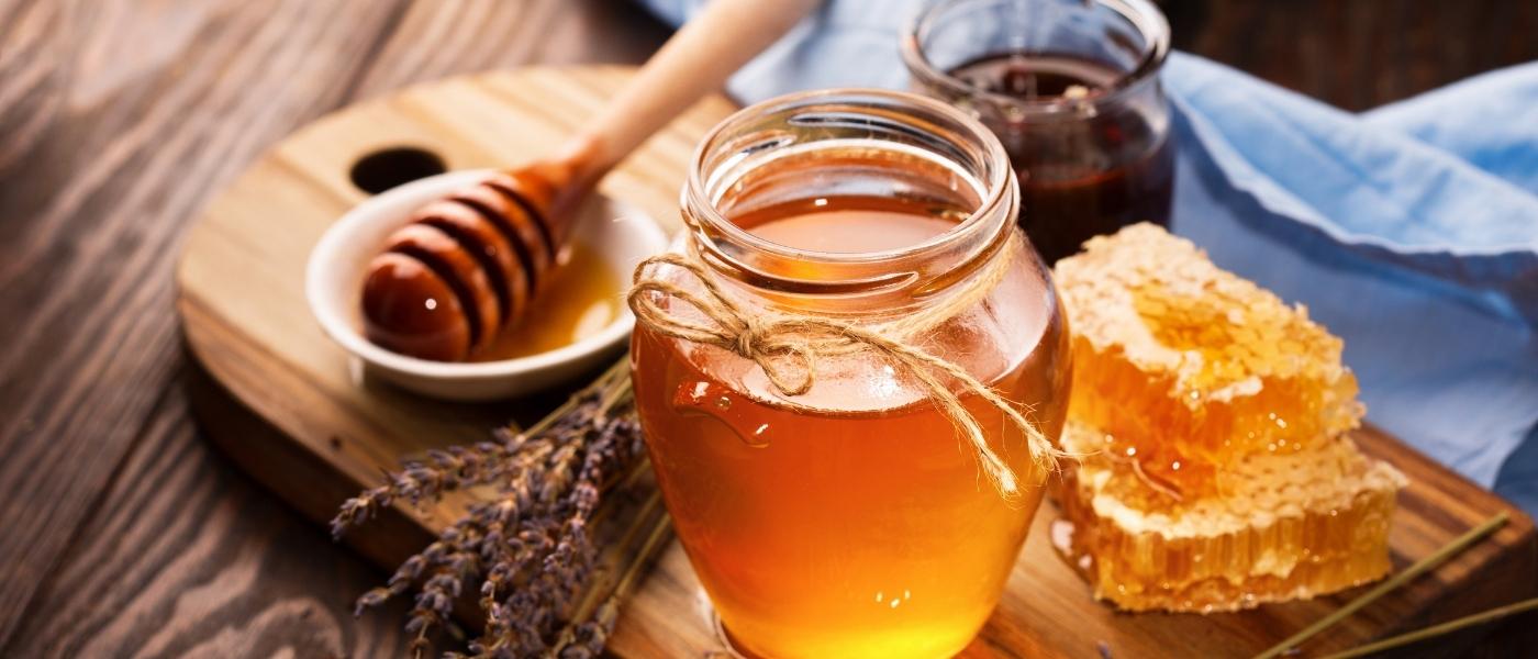 A jar of honey with honey comb and lavender