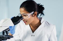 female researcher looking into microscope