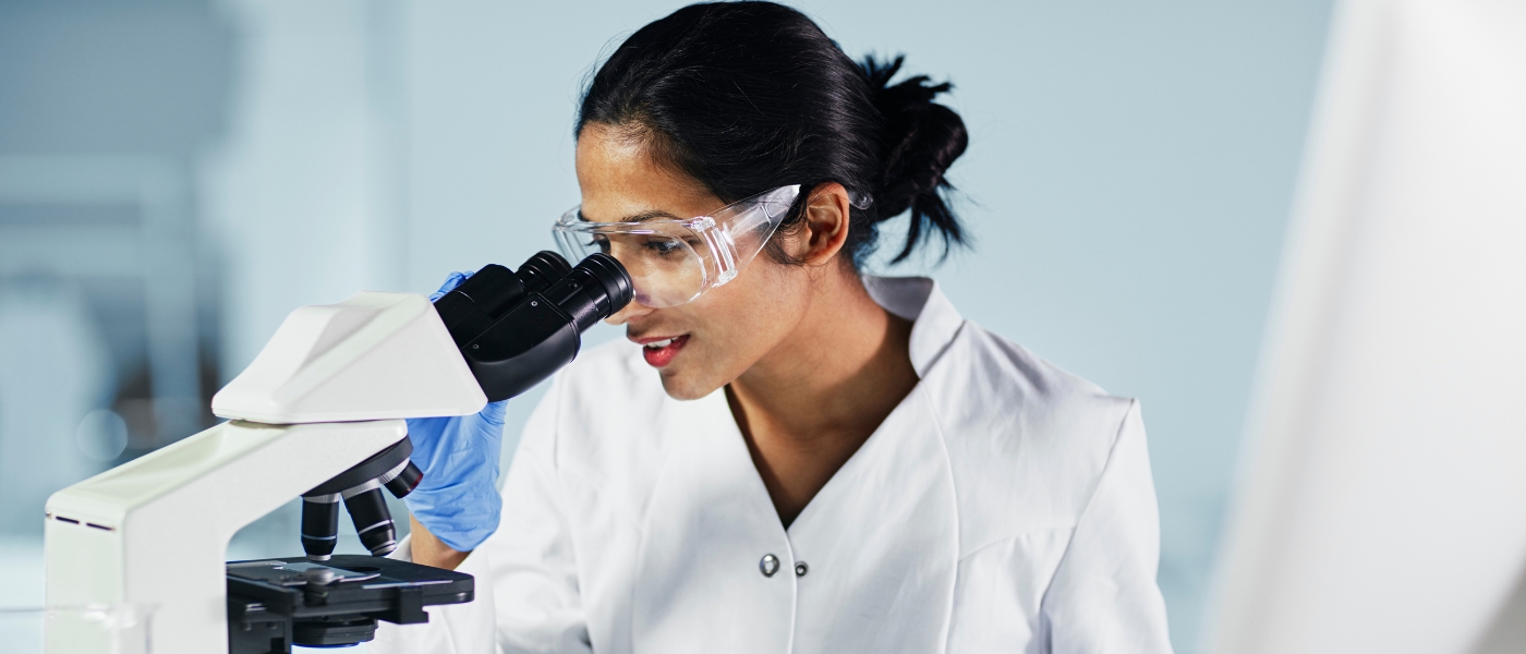 female researcher looking into microscope